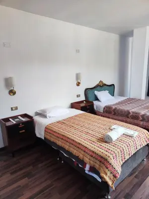 a hotel room with two beds and a night stand at Casa Conquista in Cusco