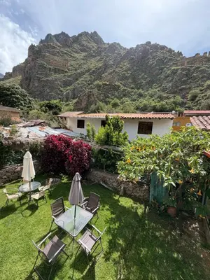 a garden with tables and chairs and mountains in the background at Anido Hotel in Ollantaytambo