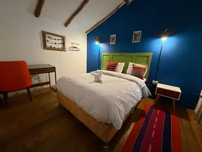 a bedroom with a bed with a blue wall at Anido Hotel in Ollantaytambo