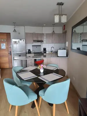 a kitchen with a dining table and blue chairs at Departamento con vista al Circuito Mágico del Agua in Lima