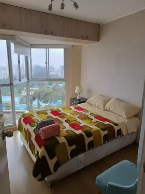 a bedroom with a large bed with a large window at Departamento con vista al Circuito Mágico del Agua in Lima
