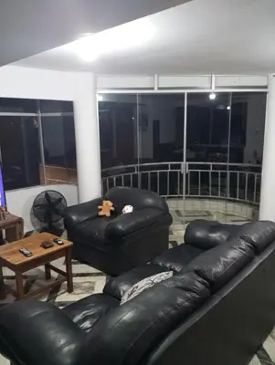 a living room with black leather furniture and a balcony at Apartamento con vista espectacular al Valle Sagrado de los Incas in Urubamba