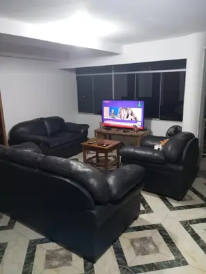 a living room with black leather furniture and a flat screen tv at Apartamento con vista espectacular al Valle Sagrado de los Incas in Urubamba