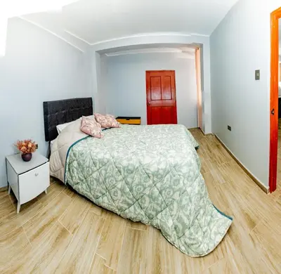 a bedroom with a large bed and a wooden floor at La covacha de viejo in Jauja