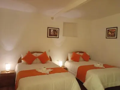 a bedroom with two beds with orange and white pillows at La casa de Goya in Cusco