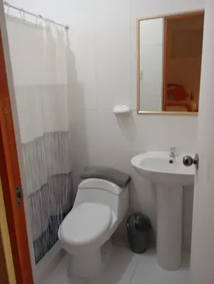 a white bathroom with a toilet and a sink at La casa de Goya in Cusco