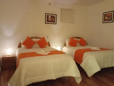 a bedroom with two beds with orange and white sheets at La casa de Goya in Cusco