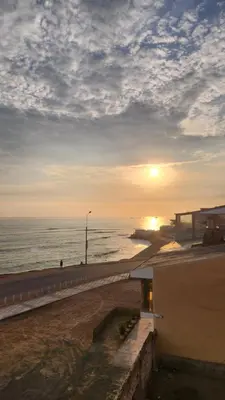 a sunset on a beach with the ocean and a building at Macky'sThe Silence in Bombiso