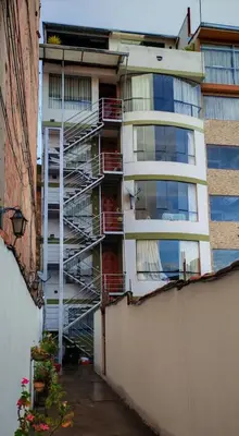 an apartment building with a fire ladder in front of it at La esquina de vallecito in Cusco