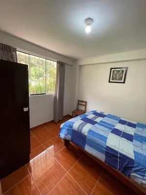 a bedroom with a bed and a large window at La esquina de vallecito in Cusco