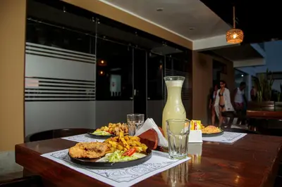 a table with two plates of food and a bottle of juice at Hotel Kendari - Chincha in Chincha