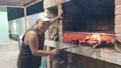 a man is standing in front of a brick oven at Villa MAS - Condominio Hacienda II in Pachacamac