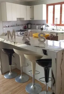 a kitchen with a large white counter with bar stools at Villa MAS - Condominio Hacienda II in Pachacamac