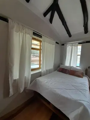 a bedroom with a white bed and two windows at Pisonaywasi - Hospedaje familiar in Urubamba