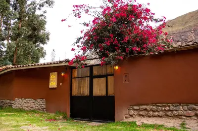 a house with a black door with pink flowers on it at Casa de La Chola in Ollantaytambo