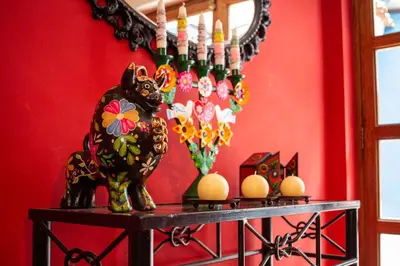 a table with a statue of a dog on a red wall at Casa de La Chola in Ollantaytambo
