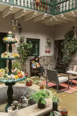 a woman sitting in a chair in a patio with plants at La Casona Real Cusco in Cusco