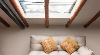 a white couch with two pillows sitting under a window at La Casona Real Cusco in Cusco