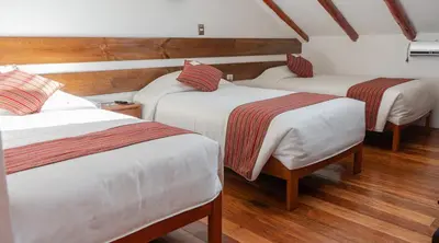 three beds in a room with wooden floors at La Casona Real Cusco in Cusco