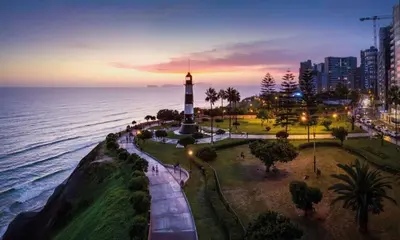 a lighthouse in a park next to the ocean at night at No available in Lima