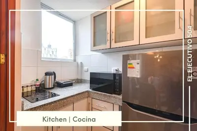 a kitchen with wooden cabinets and a black appliance at Vibrant Exclusive 1BR Apt in front of Casa Andina in Lima