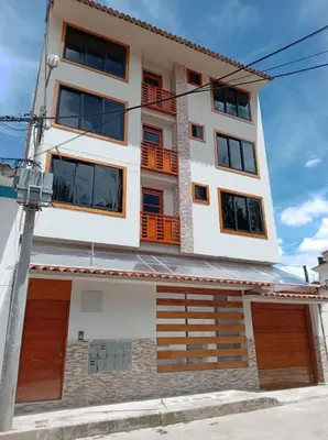 a white building with orange doors and windows at Retama Lodging in Cusco