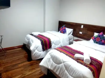 a room with three beds in a room with wooden floors at Retama Lodging in Cusco