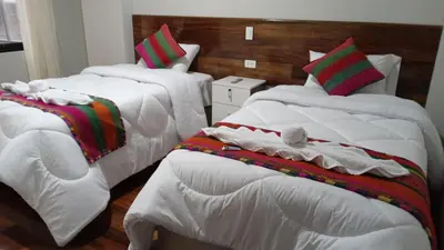 a bedroom with two beds with white sheets and blankets at Retama Lodging in Cusco
