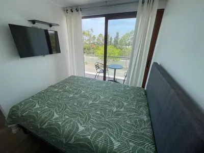 a bedroom with a bed and a tv and a window at Casa de campo en condo cerca a playa Puerto Viejo in San Antonio