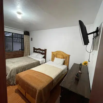 a bedroom with two beds and a television in it at Cuarto A en La Warida House in Ayacucho