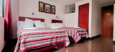 a bedroom with two beds and a red door at Plaza Hotel Huánuco in Huánuco