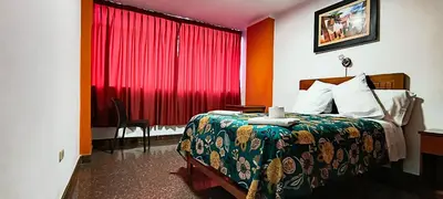 a hotel room with a bed and a red curtain at Plaza Hotel Huánuco in Huánuco