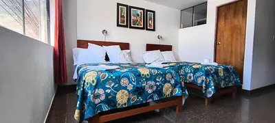a hotel room with two beds and a door at Plaza Hotel Huánuco in Huánuco