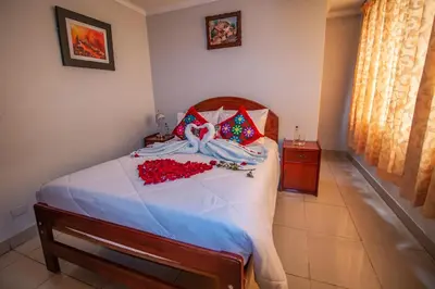 a bedroom with a bed with white sheets and red pillows at AloInkaHotels in Cusco