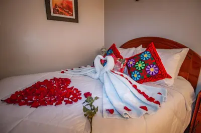 a bed with a white blanket and roses on it at AloInkaHotels in Cusco