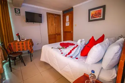 a bedroom with a white bed with red pillows at AloInkaHotels in Cusco