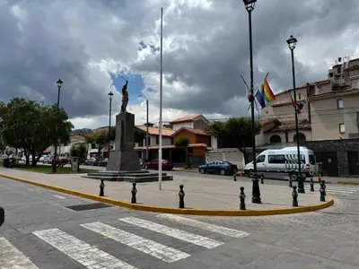 a statue in the middle of a street with flags at Templo de la Luna Pardo in Cusco