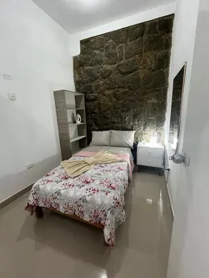 a bedroom with a bed and a stone wall at Albano apartamento 3 en tu refugio Chosica in Chosica