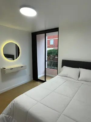 a bedroom with a large white bed and a mirror at Habitaciones casa Bella in Lima
