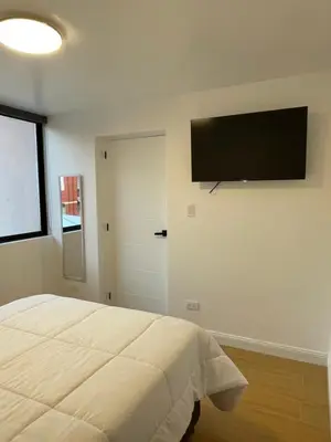 a bedroom with a bed and a flat screen tv on the wall at Habitaciones casa Bella in Lima
