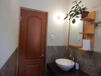 a bathroom with a sink and a wooden door at Casa Higospampa, 2 Floors Up to 7 Residents in Urubamba