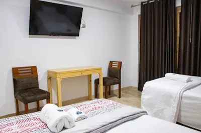 a room with two beds and a desk and a tv at Hotel Boutique La Angostura II in Ica