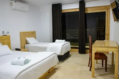 a room with two beds and a table and a desk at Hotel Boutique La Angostura II in Ica