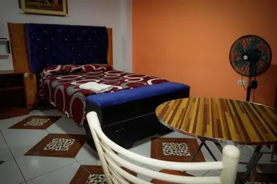 a bedroom with a bed and a table and a fan at Hostal Luren - Parking in Nazca
