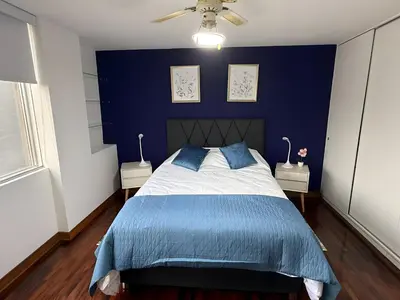 a bedroom with blue walls and a bed with blue sheets at Dpto Benavides la paz miraflores in Lima