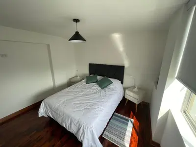 a bedroom with a bed with white sheets and green pillows at Dpto Benavides la paz miraflores in Lima