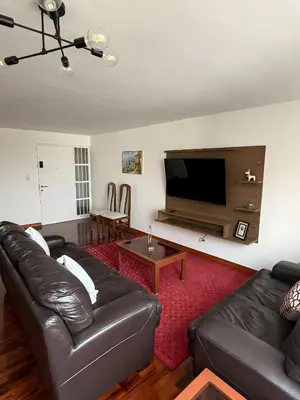 a living room with a leather couch and a flat screen tv at Dpto Benavides la paz miraflores in Lima