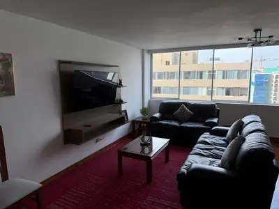 a living room with a couch and a flat screen tv at Dpto Benavides la paz miraflores in Lima