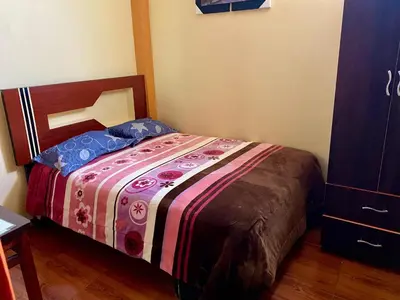 a bedroom with a bed with a colorful blanket at Hospedaje Samarina in Acobamba