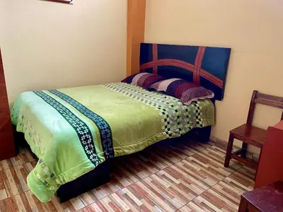 a bedroom with a bed with a wooden head board at Hospedaje Samarina in Acobamba